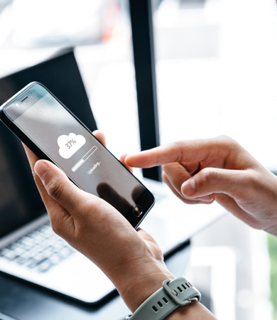 A woman at desk uploading to cloud on phone